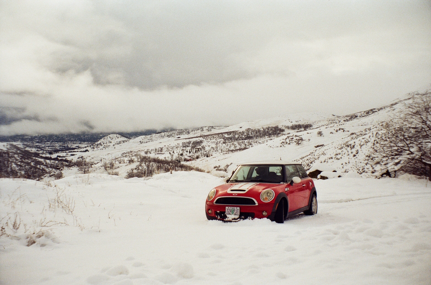 A photo of a red mini cooper in a snowy mountain landscape