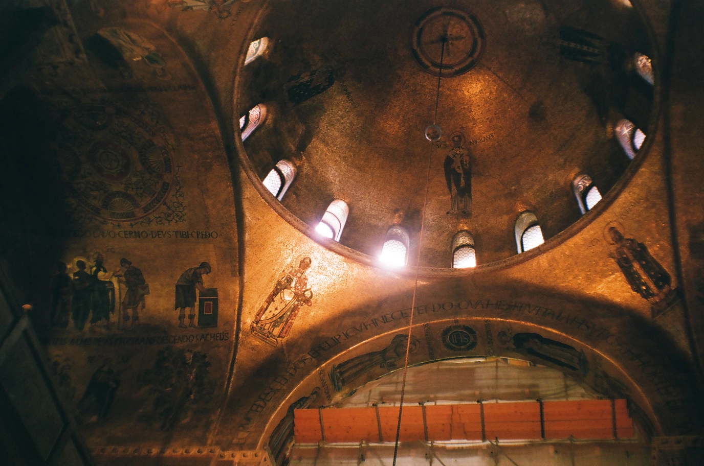 A photo of the sun beaming through windows of a gold plated church