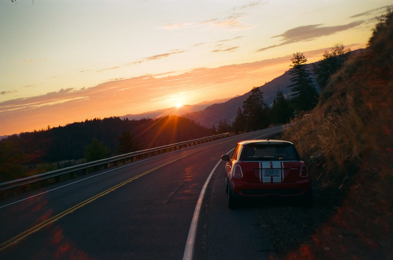 A photo of a red mini cooper and the setting sun