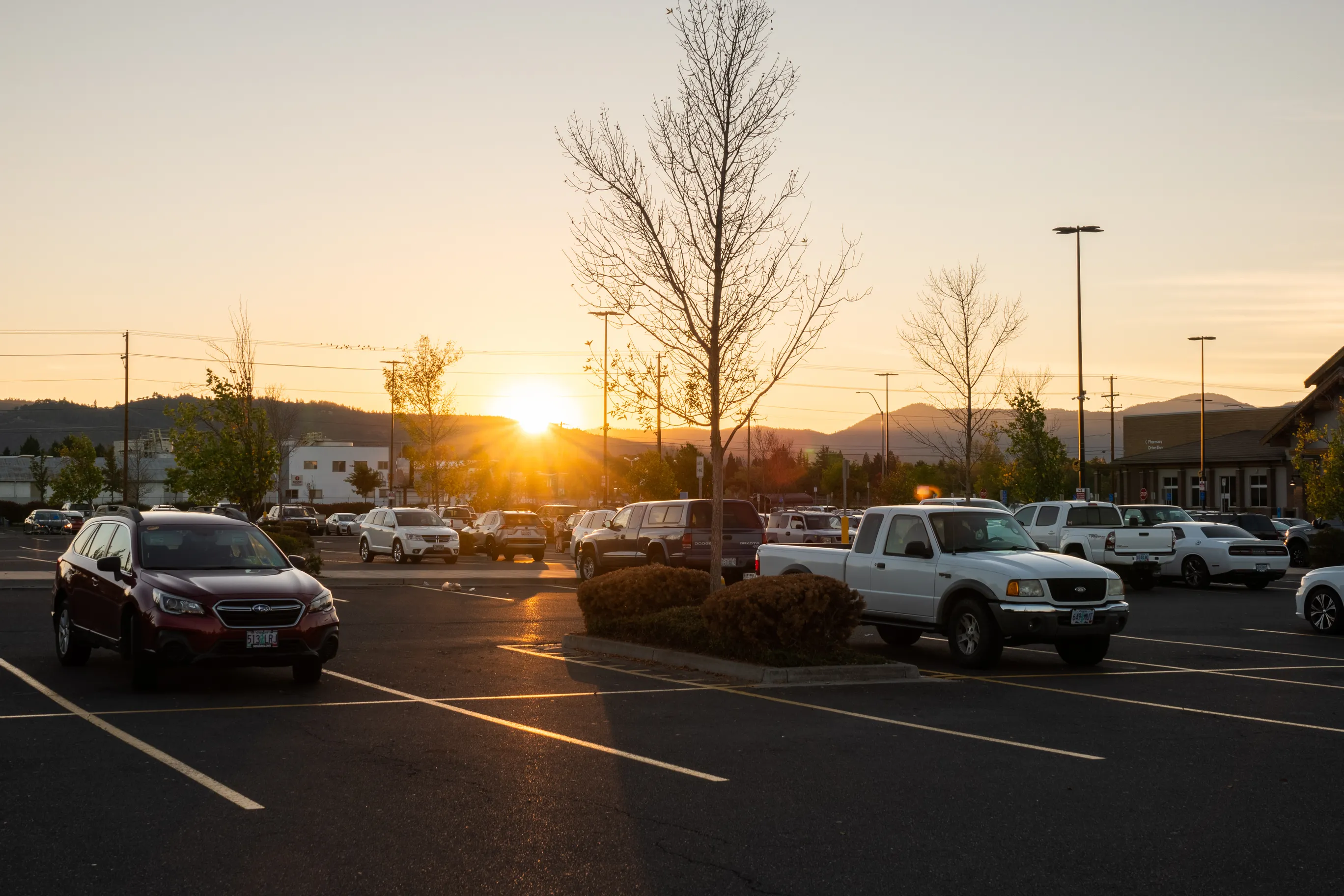 A photo of the sun on the horizon in a walmart parking lot