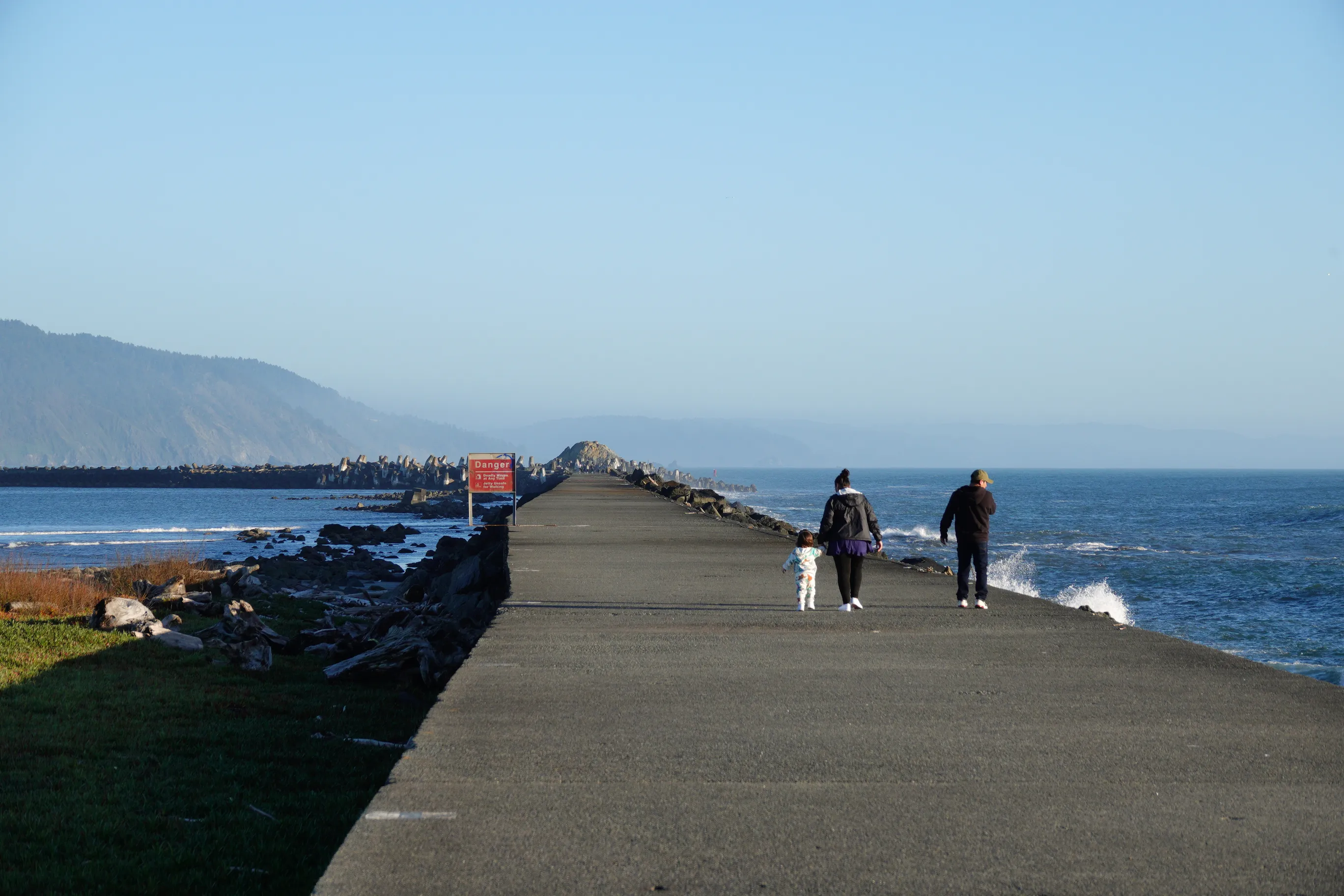 A photo of a toddler and their parents walking down a long pier