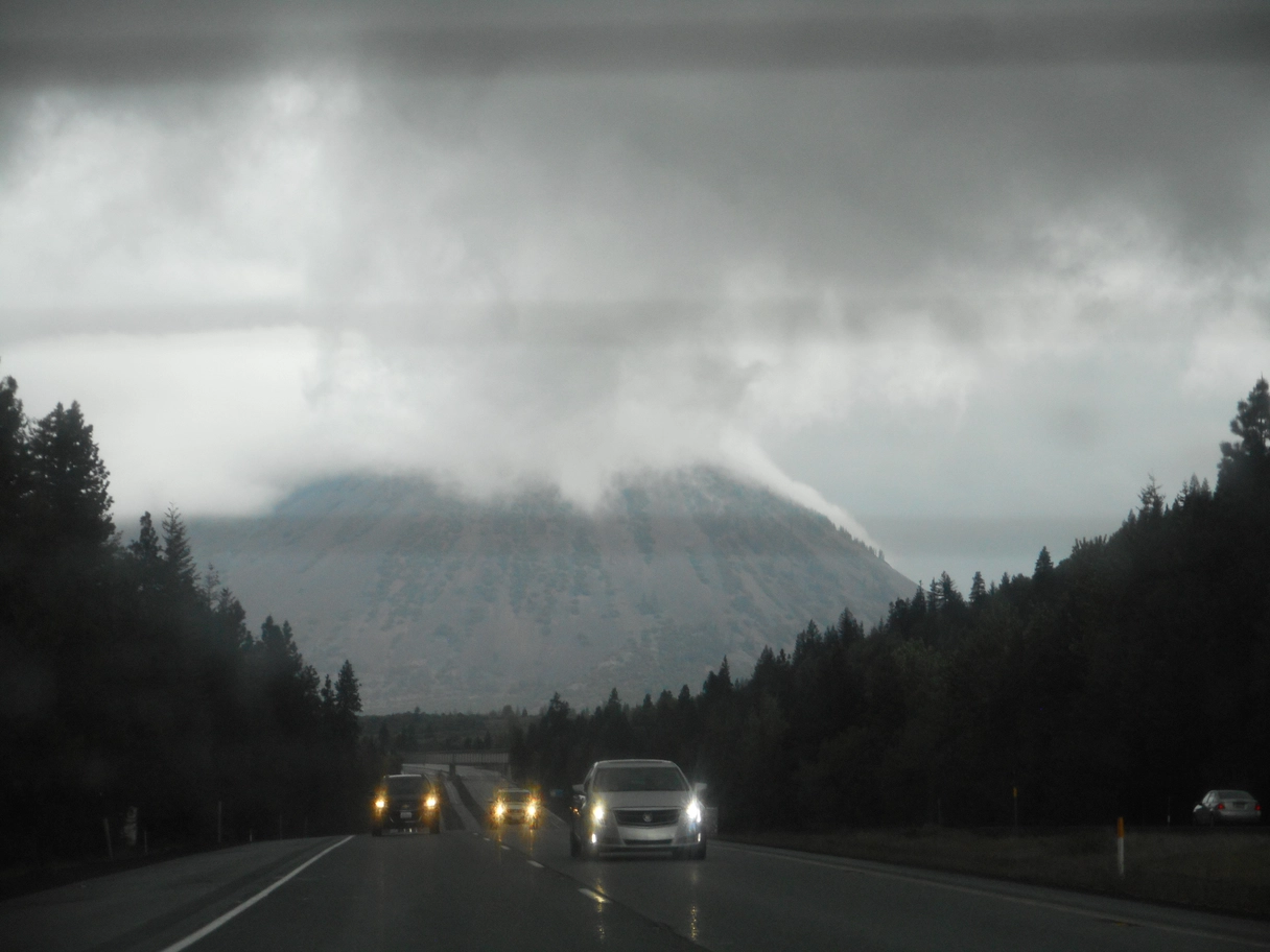A photo of big mountain with clouds and cars