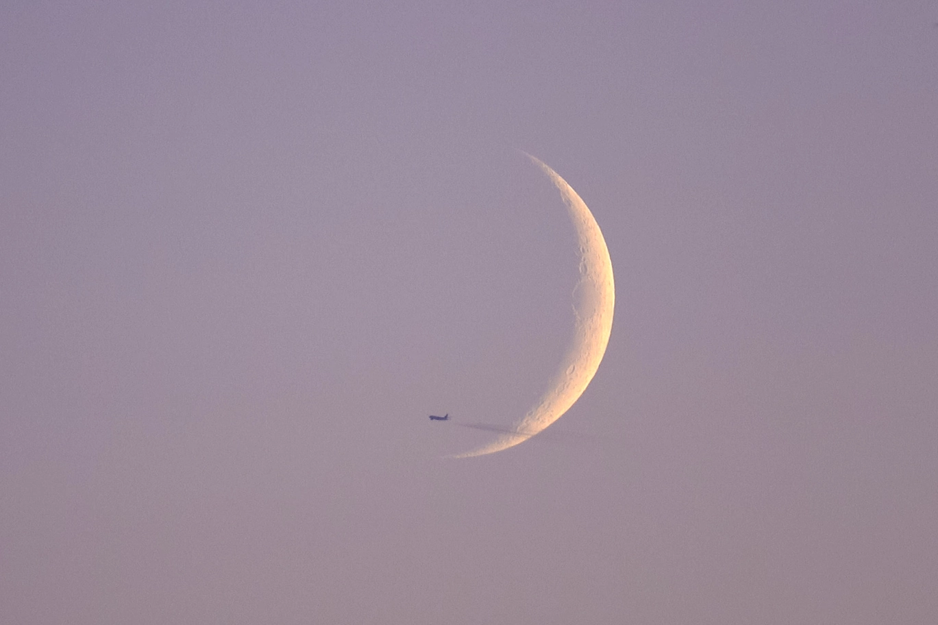 A photo of an airplane flying in front of the moon