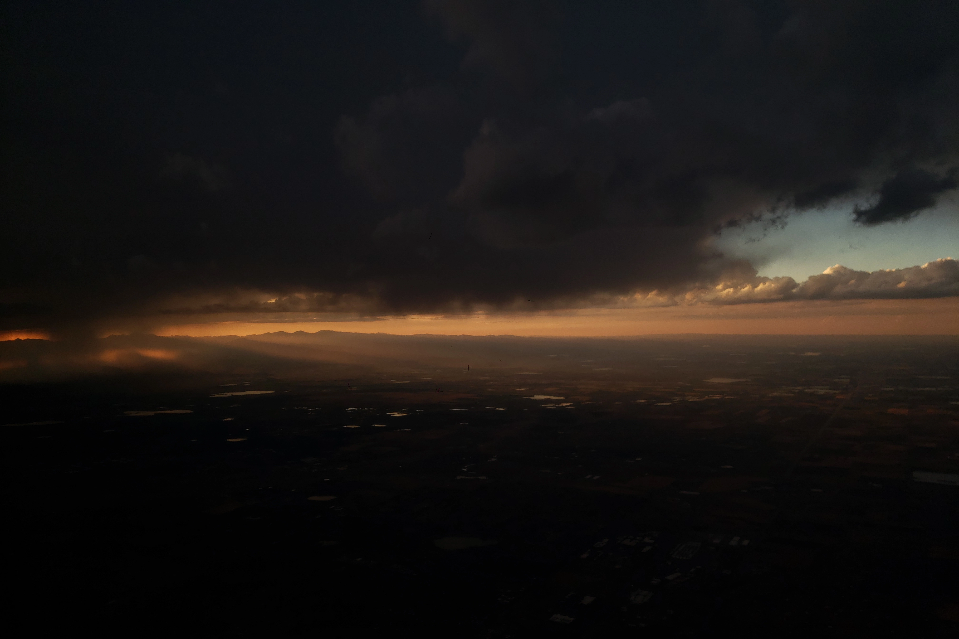 A photo of the sun beaming through the clouds from an airplane