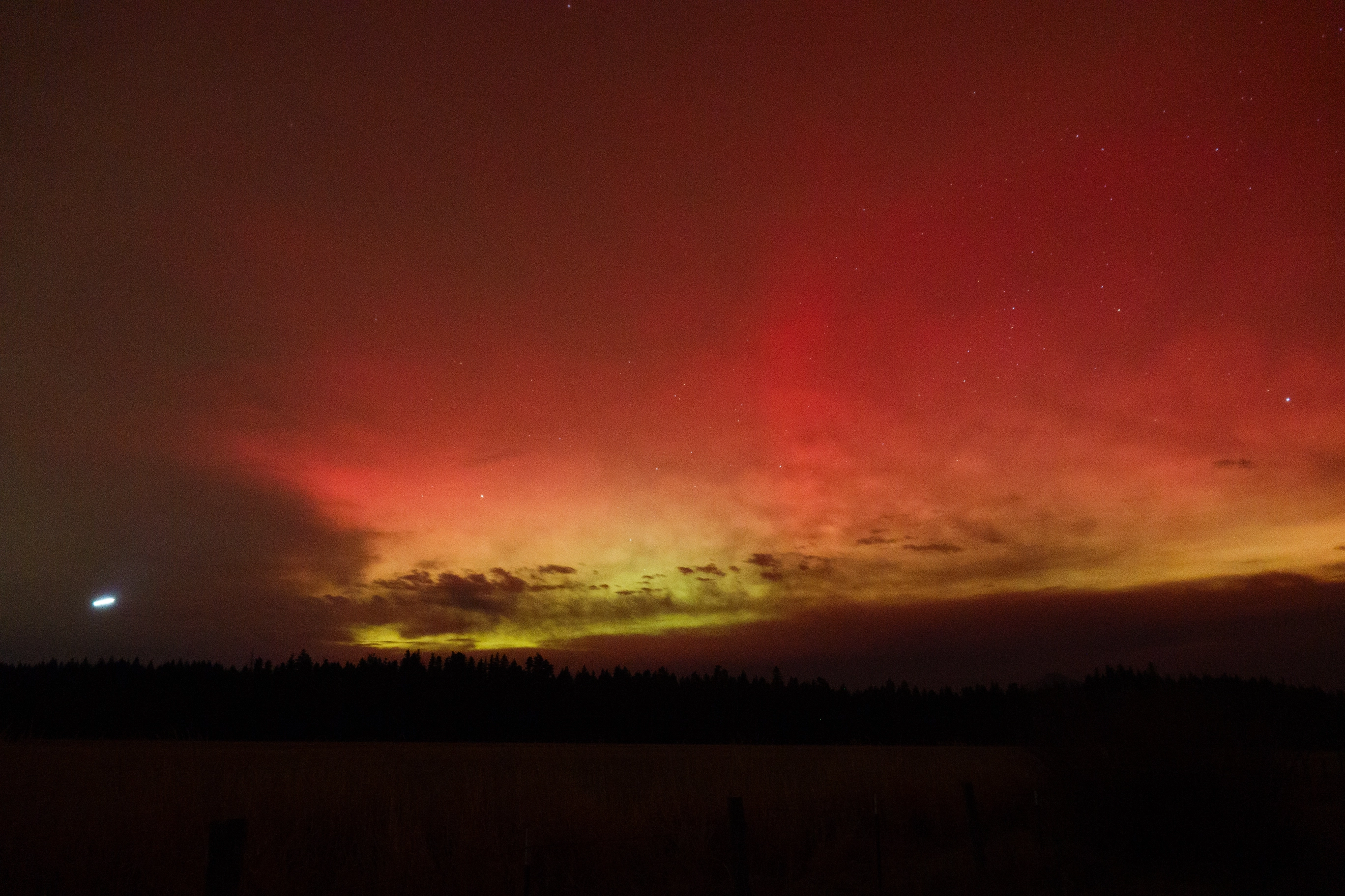 A photo of red and green auroras with clouds