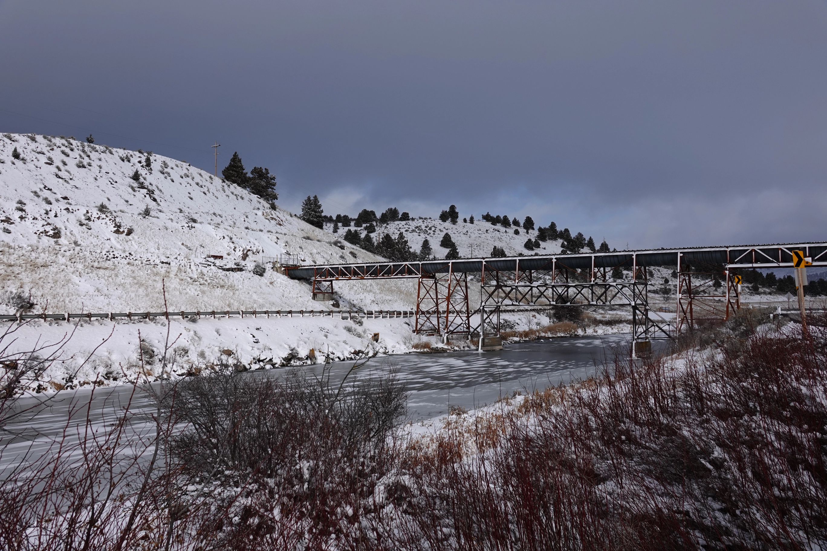 A photo of an aqueduct(?) bridging across a frozen, snowy river