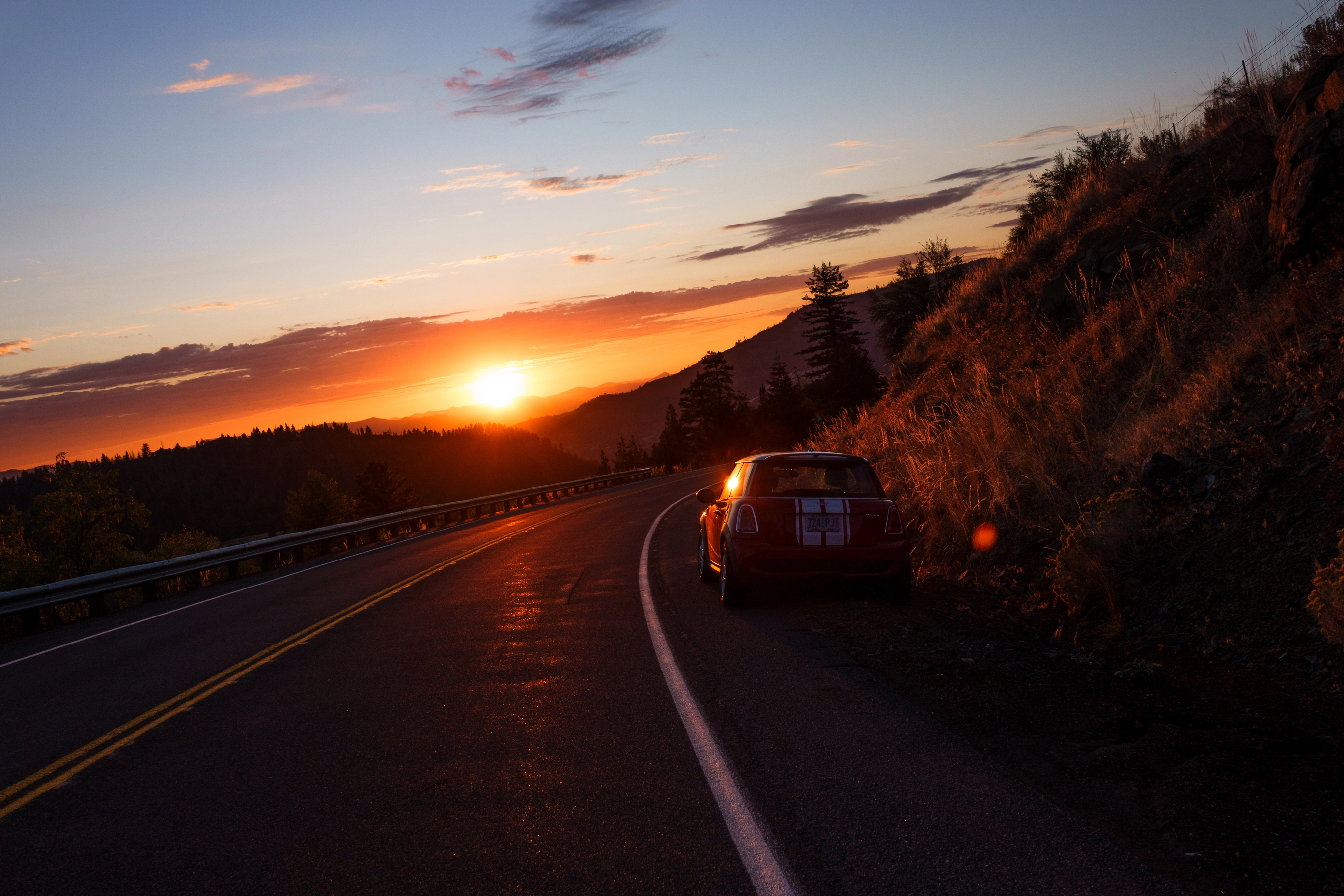 A photo of a red mini cooper and the setting sun