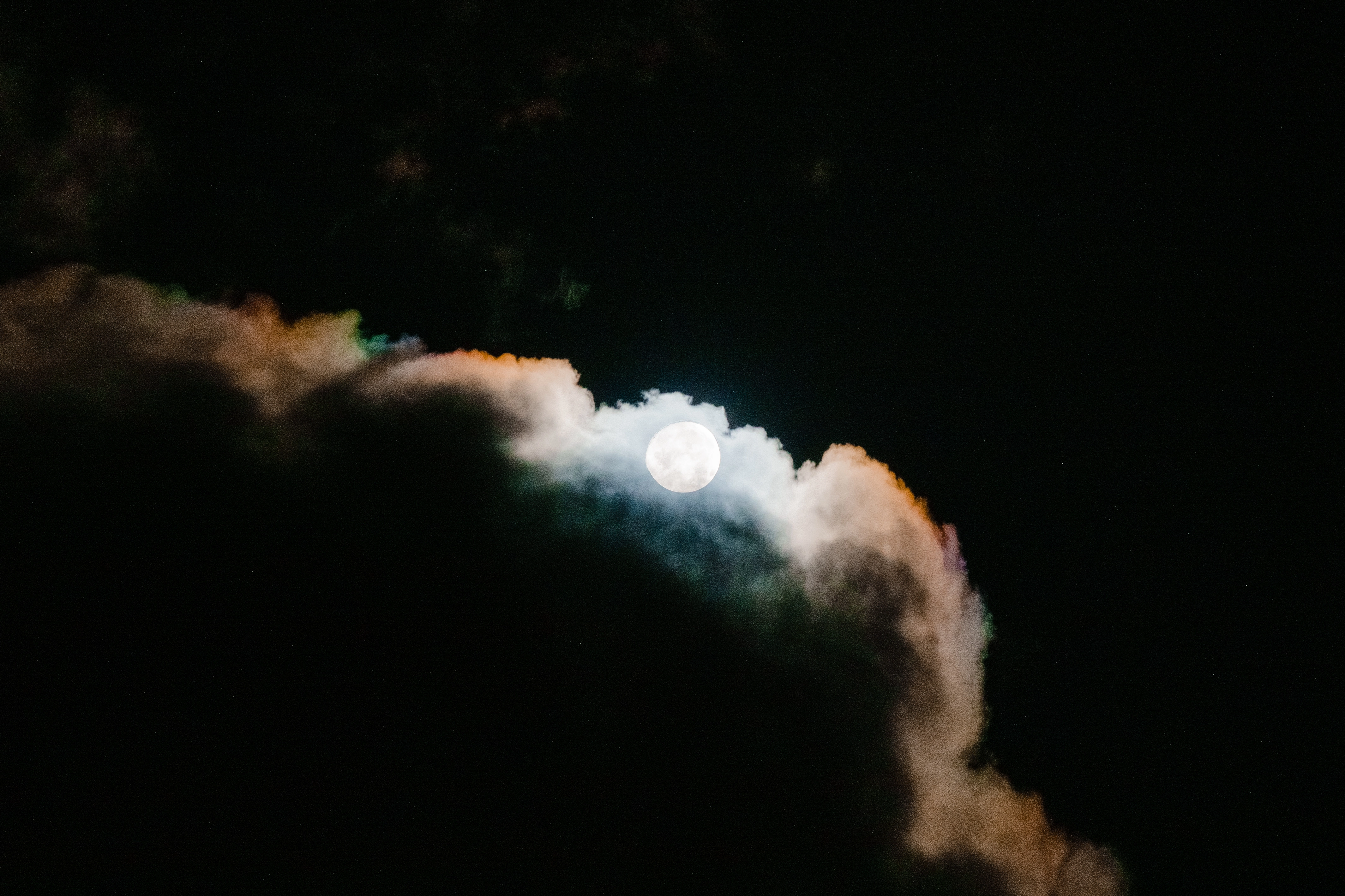 A photo of the moon coming out from behind clouds