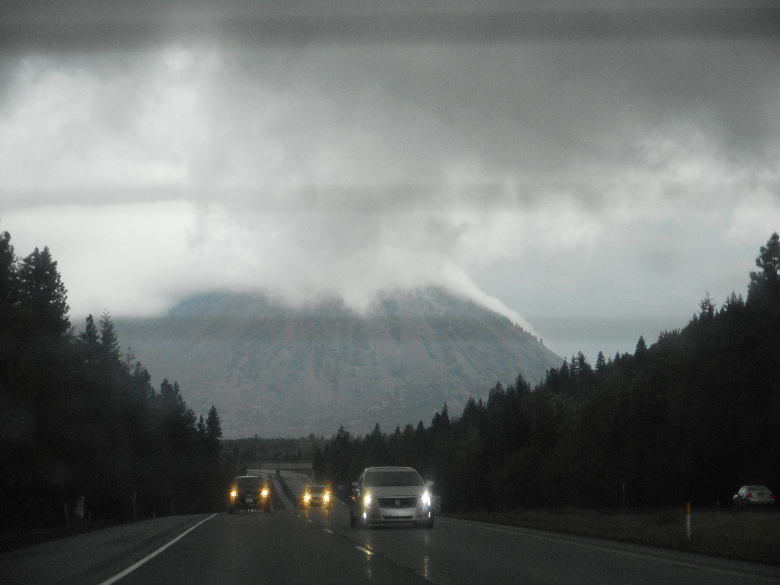 A photo of big mountain with clouds and cars